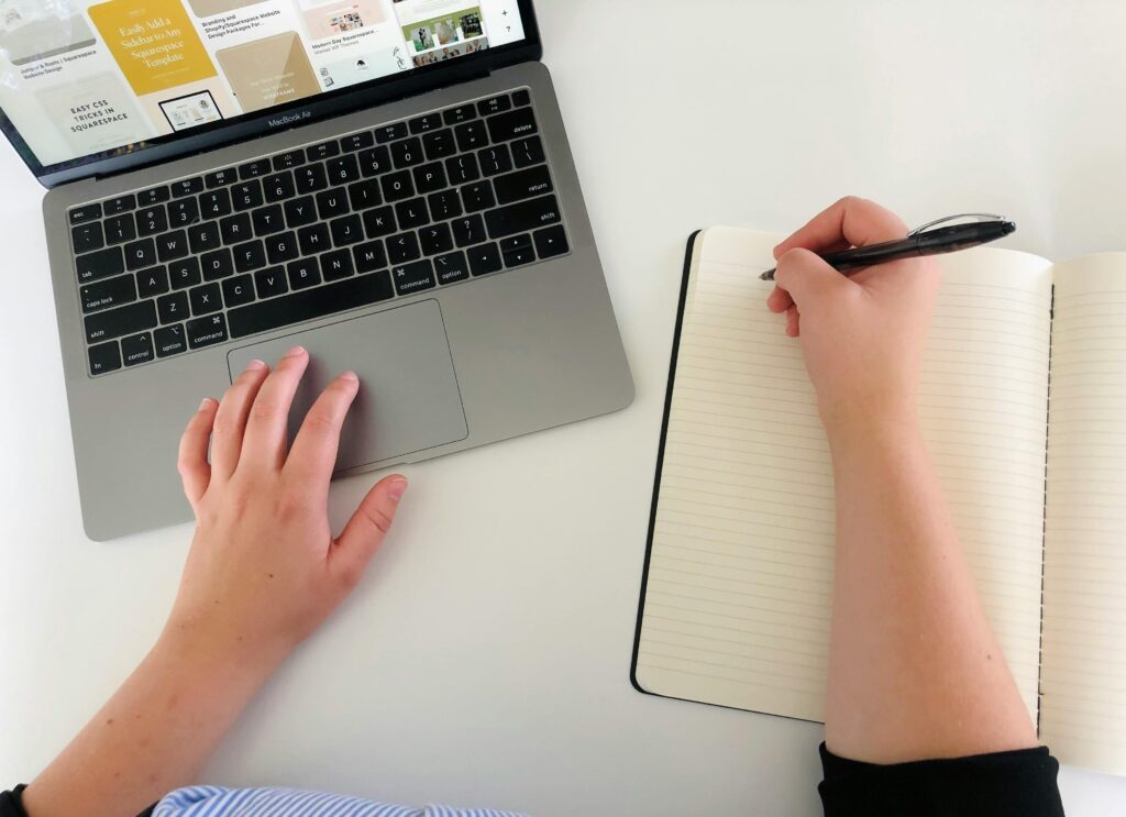Top view of a woman working remotely with a laptop and notebook, showcasing productivity and multitasking.